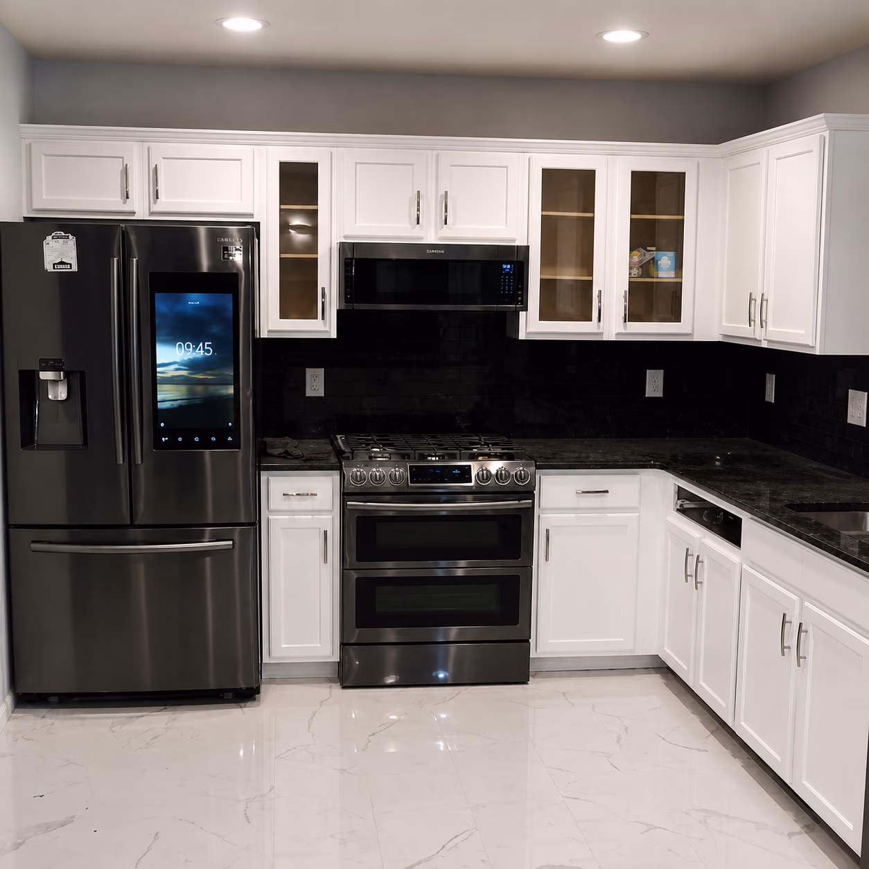 Modern kitchen with white cabinets, black countertops, stainless steel fridge, stove, and microwave.